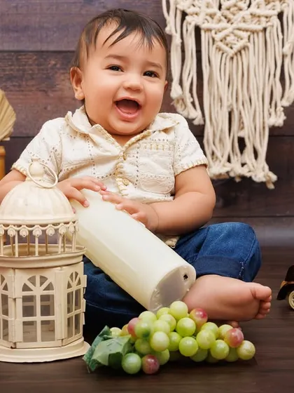 A burst of laughter from a one-year-old boy playing with props during his rustic-themed birthday shoot.