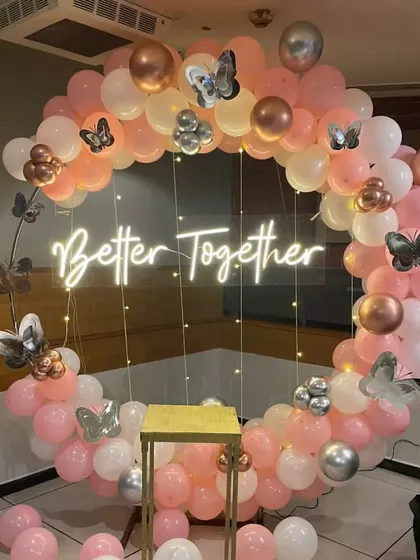 This is another 'Better Together' themed backdrop, featuring a full ring of pink, white, and chrome balloons. The design is accented with butterfly cutouts and fairy lights, creating a whimsical and romantic photo opportunity.