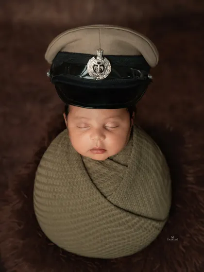 A creative and touching shot from the same session, where the newborn is safely posed wearing their father's police cap. It's a unique way to honor a family's legacy.