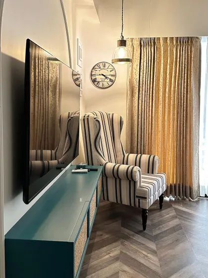 Another angle of the reading corner, highlighting the warm lighting from the industrial-style pendant lamp and the comfortable, high-back armchair.