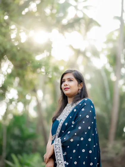 A beautiful portrait of the bride-to-be against a backdrop of lush greenery, with sunlight filtering through the trees. This shot highlights her elegance during their pre-wedding session.
