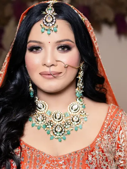 A classic bridal look with a bold orange lehenga. The makeup features a subtle smokey eye and a flawless base that will last through all the wedding ceremonies.