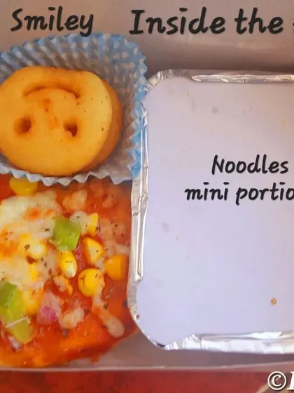Another look at our popular kids' party box, showing the mini pizza, smiley, and foil-packed noodles. We make sure the food is not just tasty but also fun to eat.