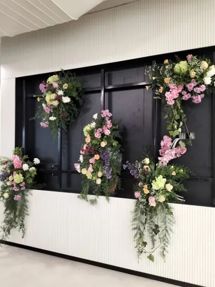 We use floral installations to transform standard office features into points of interest. This floral decor on a modern black-paneled wall added a touch of nature and sophistication to an inaugural office event, enhancing the existing architecture.