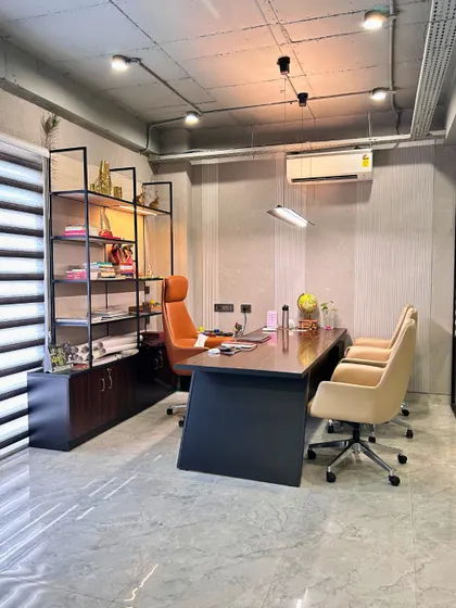 A private cabin in the corporate office, designed with a refined aesthetic. The space includes a modern desk, ergonomic chairs, and an open shelving unit for a look that is both professional and comfortable.