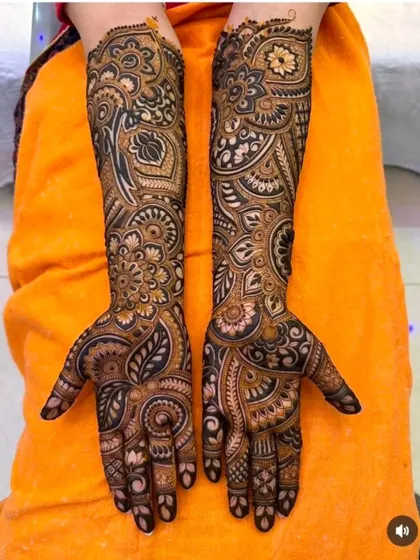 A very dense and intricate design using bold, black-toned henna for a dramatic effect, filled with paisley and floral details.