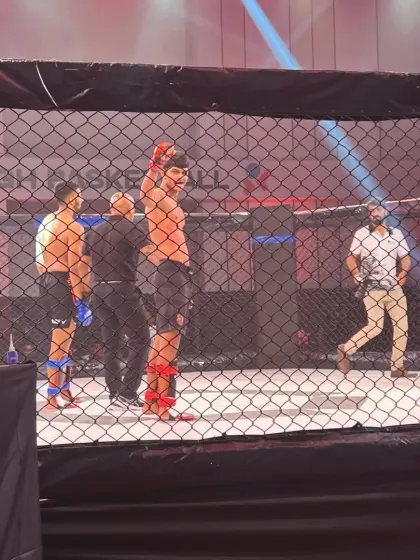 A view from outside the cage as our fighter gets his hand raised. This perspective shows the arena and the culmination of a hard-fought battle.