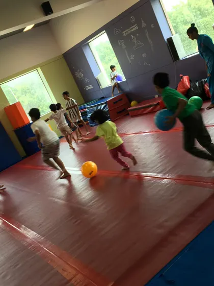A candid shot of kids running and playing a game with balls on our matted floor. There's never a dull moment at our parties.