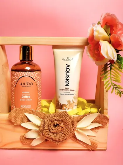A simple and elegant shot of a coffee body wash and moisturizing cream in a wooden caddy against a pink background.