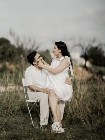 A sweet and playful moment, with the bride sitting on the groom's lap and gently pinching his cheek.
