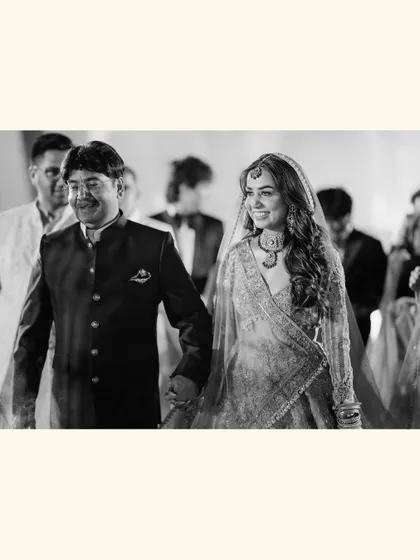 A beautiful black and white shot of bride Chitranksha walking with her father. This poignant moment captures the love and pride shared between a daughter and her dad on the wedding day.