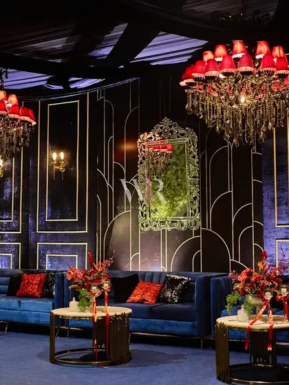 A luxurious lounge area designed for a European-themed cocktail night. We paired plush midnight blue sofas with Art Deco-inspired backdrops, ornate mirrors, and dramatic red chandeliers to create a space that felt both glamorous and intimate.