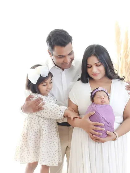 A bright and airy family portrait celebrating the new addition. This image captures the joy of a growing family, with the older sibling gently welcoming the new baby.