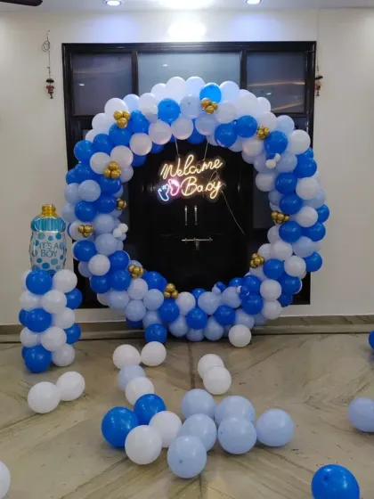 A clear view of the blue and white circular balloon arch with a "Welcome Boy" neon sign.