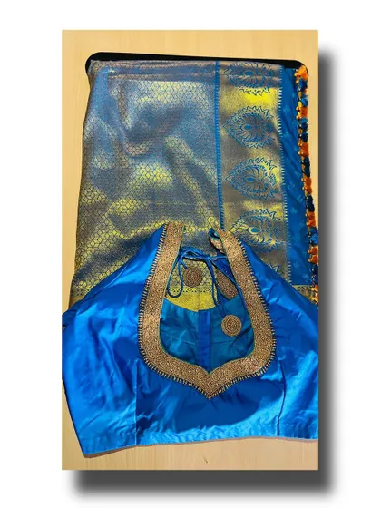 A full view of a blue silk saree paired with its custom-stitched blouse. The blouse's simple, elegant neckline with beadwork is designed to complement the saree without overpowering it.