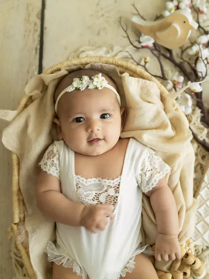 A 3-month-old angel. Dressed in a delicate white lace romper, this baby looks so serene and beautiful in our rustic, bird-themed setup.