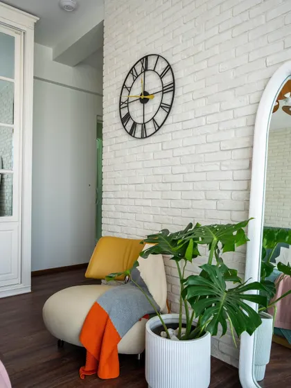 A detail shot of the reading corner in the 'Urban Oasis' bedroom, showing the large clock, wavy mirror, and comfortable seating.