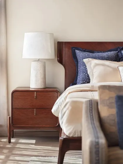 A close-up of a bedside table in the Max128 apartment, where a modern lamp and rich wood tones create a warm and inviting corner.