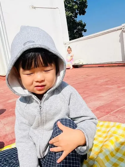 A boy enjoys the warmth of the sun while sitting on a picnic blanket on our school's terrace.
