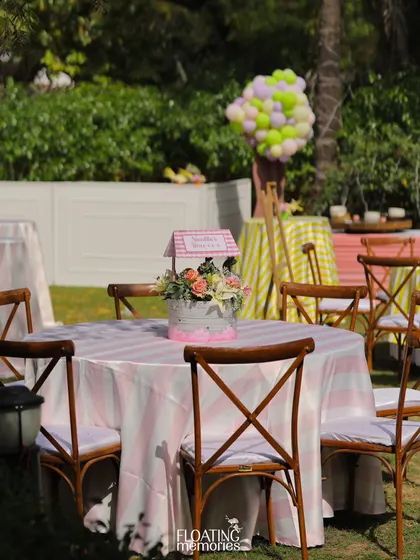 The guest seating was designed to match the theme, with pink and white striped tablecloths and charming floral centerpieces. The cross-back chairs add a rustic yet elegant touch to the outdoor birthday party setup.