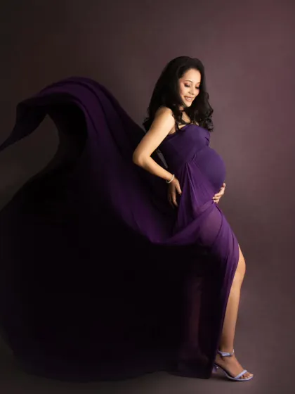 The wind-swept effect on this purple gown creates a stunning silhouette, highlighting the mom-to-be's beautiful baby bump.