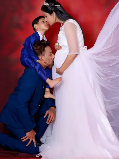 A precious family maternity photo, with the father and son both giving a kiss to the baby bump.