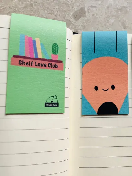 Two of my magnetic bookmark designs: the "Shelf Love Club" for book collectors and a happy little pencil.