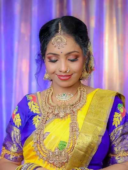 A serene bridal portrait. The bride's eyes are closed, showcasing her beautiful eye makeup. The heavy gold jewelry and yellow silk saree complete the classic South Indian bridal look.