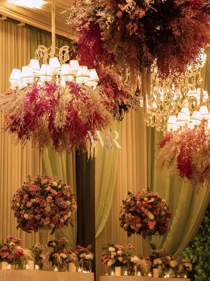 Chandeliers get a floral makeover. For this event, we dressed modern chandeliers with clouds of colorful dried and preserved flowers, creating unique lighting fixtures that became a central design feature.