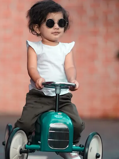 A cool little dude on his ride-on car. The brick wall background adds an urban, edgy vibe to the photo.