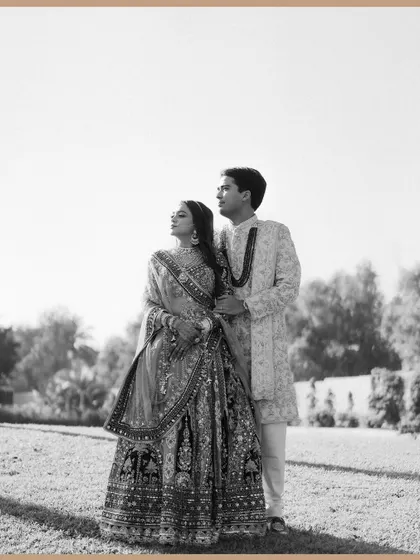A classic black and white portrait of the couple standing in an open field. The composition is simple yet powerful, emphasizing their connection and the timeless elegance of the moment.