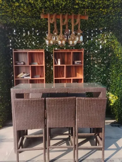 We created this cozy outdoor bar and seating area using a trellis structure covered in artificial leaves. The setup includes a high table and shelving, perfect for entertaining.