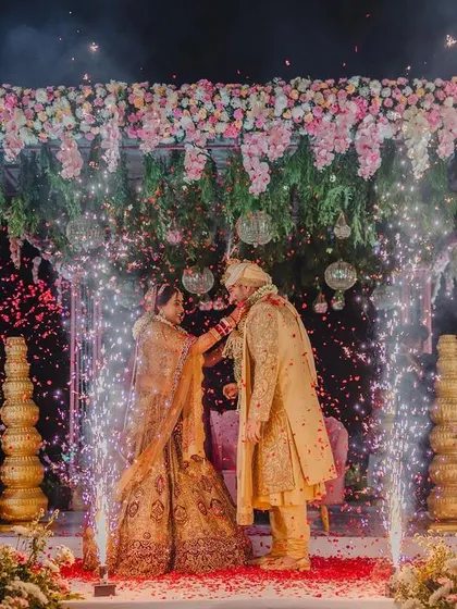 A magical Varmala exchange, complete with cold pyro sparklers, set against a beautiful floral mandap at a destination wedding.
