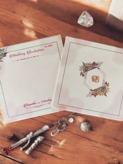 A luxurious metallic paper card with exquisite floral watercolor designs and personalized acrylic initials, suitable for multiple ceremonies.