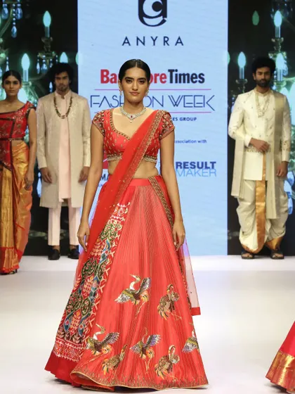 This runway look highlights the innovative silhouette of the Patola saree lehenga. Paired with a simple netted dupatta and an embroidered blouse, the focus remains on the intricate weave of the Patola and the detailed zardosi work.
