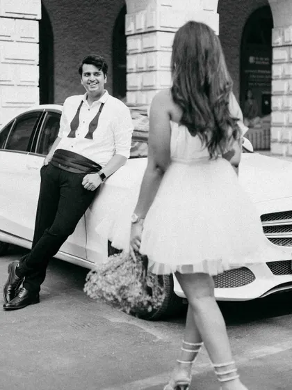 A playful, candid moment during our vintage car shoot. The way she approaches him with a smile captures a sense of fun and anticipation, adding a story to the stylish setup.