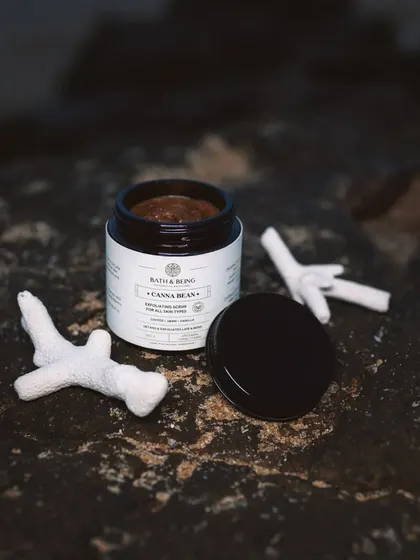 This is our Canna Bean scrub, made with coffee, walnut, and hemp. It’s a luxurious blend that exfoliates, cleanses, and hydrates your skin with ingredients like cold-pressed coffee oil and granulated organic coffee.
