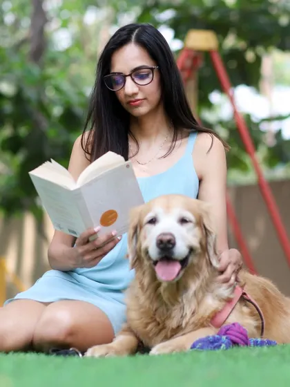 A peaceful afternoon in the garden, where Anjana reads a book with her best friend Abby resting calmly by her side.