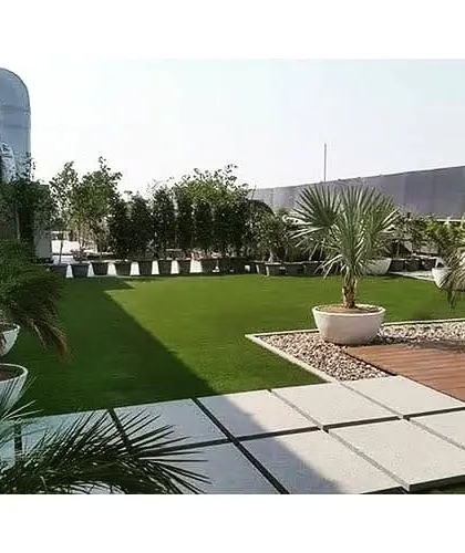This terrace garden combines a lush artificial lawn with large potted plants and a wooden deck. It's a perfect low-maintenance solution for creating a beautiful and usable rooftop space.
