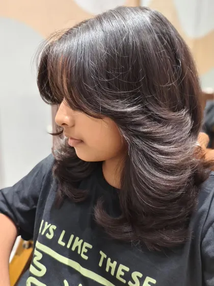 A beautiful butterfly haircut on a younger client, giving her a trendy and stylish look.