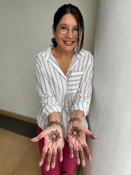 A happy client showing off her first-ever henna, a simple and beautiful geometric design on her palms.