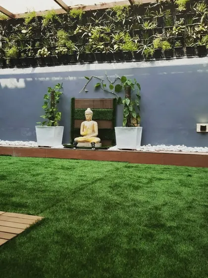 A terrace garden is incomplete without a Buddha statue. Here, it is placed in front of a large vertical garden, creating a wall of green.