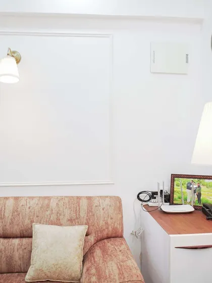 A quiet corner in a living room, featuring simple wall beading and a comfortable sofa. A floor lamp provides warm, focused light, creating a perfect spot for reading or relaxing.