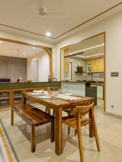 The dining area is anchored by a solid wood table and bench, situated between the open kitchen and a view of the powder room's textured tile wall.
