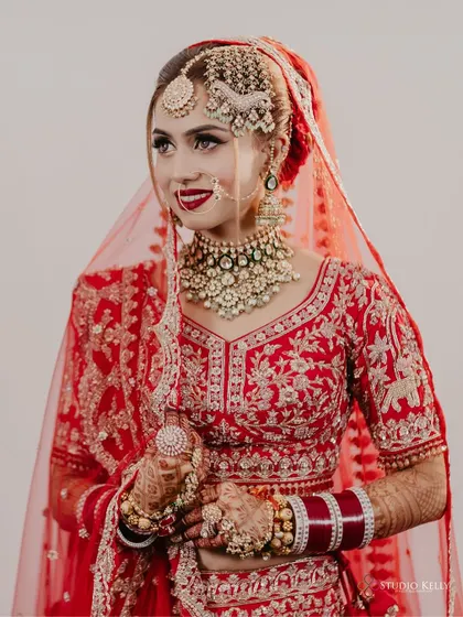 A classic portrait of the bride in her red lehenga, showcasing her intricate jewelry and beautiful smile.