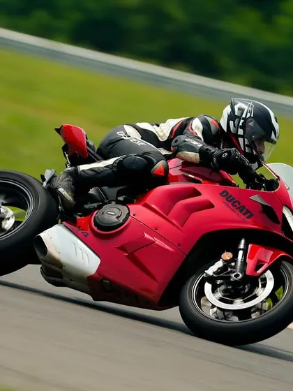 A Ducati Panigale V4 in action at Madras International Circuit, its red paint standing out against the green background as it powers through a turn.