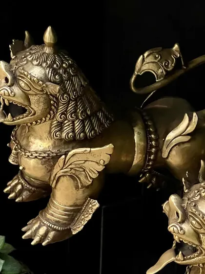 A close-up of the brass Tibetan temple lion. The intricate details in the mane and the fierce expression are a testament to the artisan's skill, creating a powerful guardian for your home.