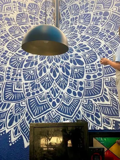 Painting a large scale mandala mural for a restaurant. The bold white design on a deep blue wall creates a dramatic and memorable visual impact.