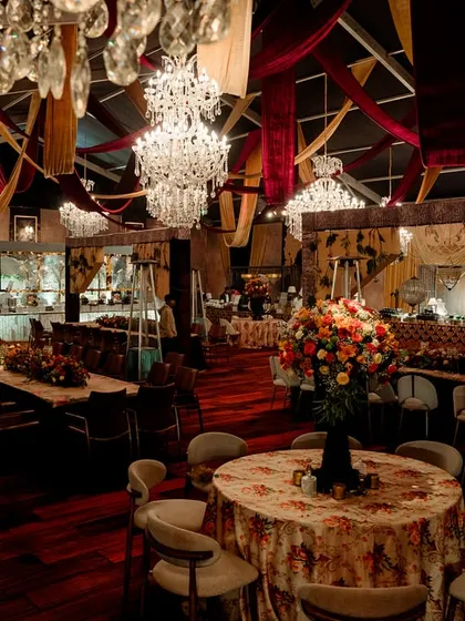 Another view of the dining space, showing the long tables and round tables arranged for guests. The warm lighting from the chandeliers creates an inviting and celebratory mood.