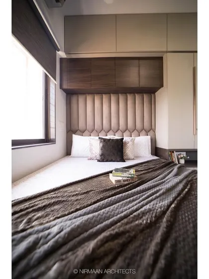 This compact bedroom is designed to feel cozy and enveloping. The upholstered headboard and overhead cabinets maximize storage while creating a snug sleeping nook.